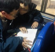 两名学生公交车上看书学习 不顾人声嘈杂边看边讨论