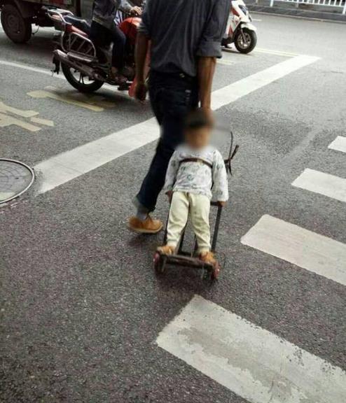 男子将小孩绑在推车上过马路 网友：这绝对是亲生的