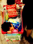 女子推着购物车带娃逛超市 萌娃车里安然入梦