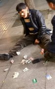 醉汉瘫坐街头  还将身上现金甩一地
