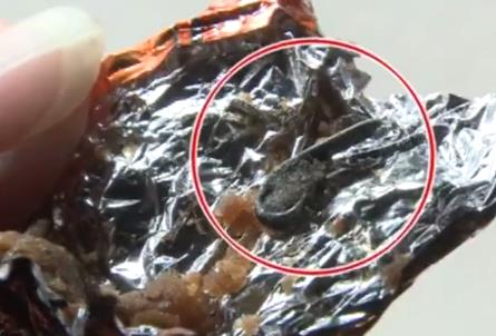 张女士赶紧吐出来一看，是一个铁钉状的黑色异物。黑色铁质异物盘成一圈，中间裹着牛肉粒，一头较为锐利。