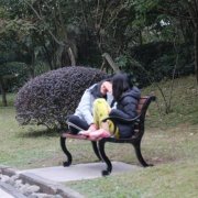 女子脚踩公园座椅  盘腿而坐聊得欢