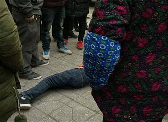 小男孩不进学校躺地不起 路人拉他反被踢一脚