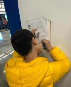 男孩把候车墙面当书桌 边作业边等车很投入
