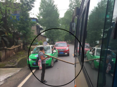 女子情绪激动用木棒堵路 大巴出租都被拦在了路上