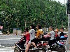 两位女司机驾电动车等红灯 双双超载似比赛