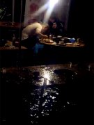 暴雨中道路积水 两男子蹲凳子上涮火锅