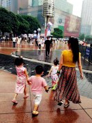 女子步行街上一手系三娃引围观 画风逗趣幸福