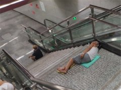 轨交站扶梯处变“纳凉亭”  大爷打地铺睡觉